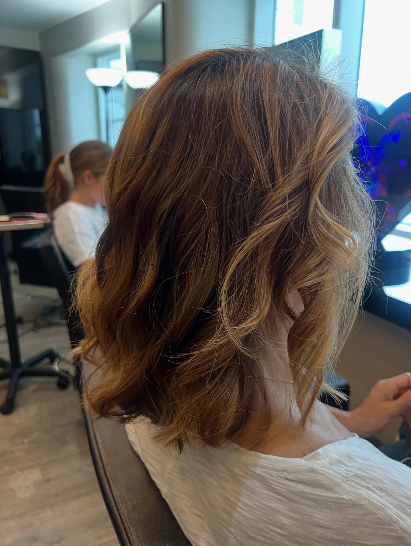 Soft, shoulder-length waves with warm caramel balayage, seen from behind