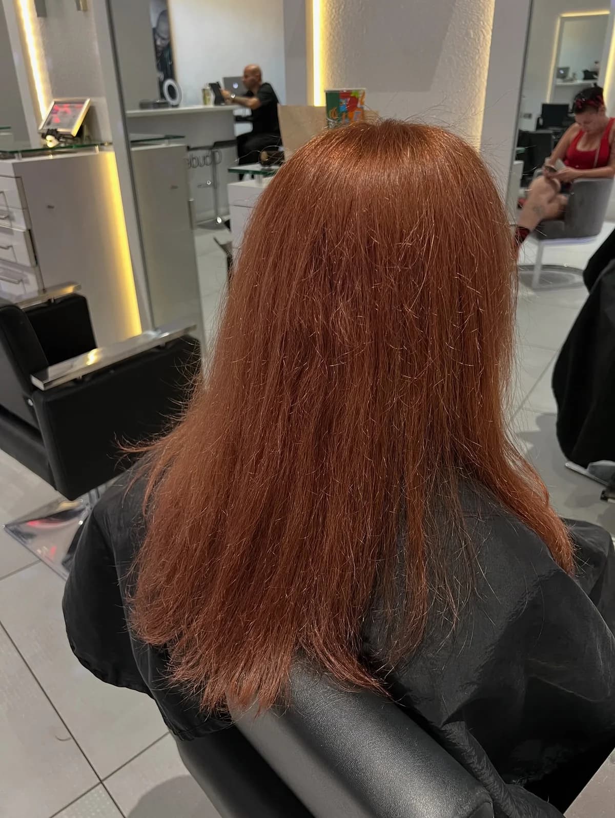 Copper color correction in progress, with straight hair viewed from behind in the salon