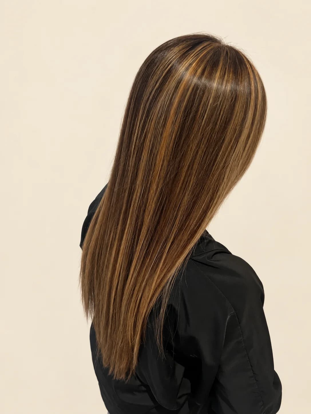 Long, sleek brunette hair with warm caramel highlights, seen from behind