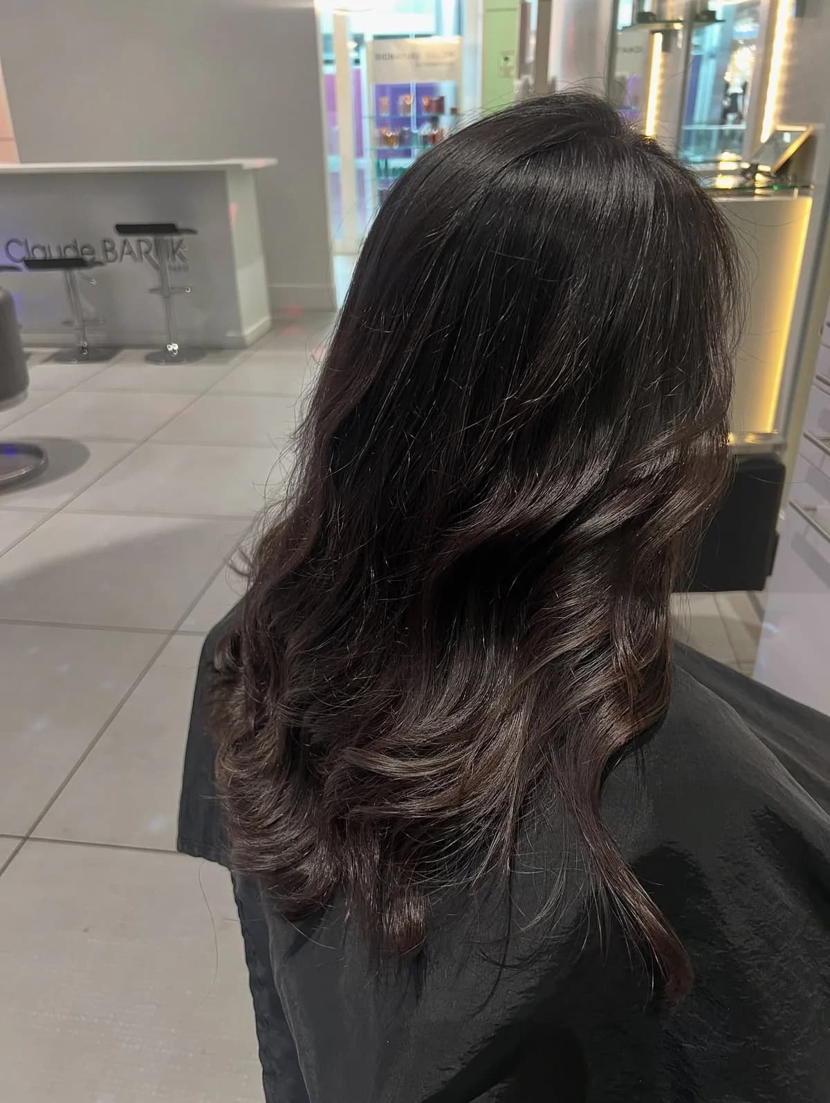 Long, glossy dark brunette hair with soft waves, photographed from behind in a salon