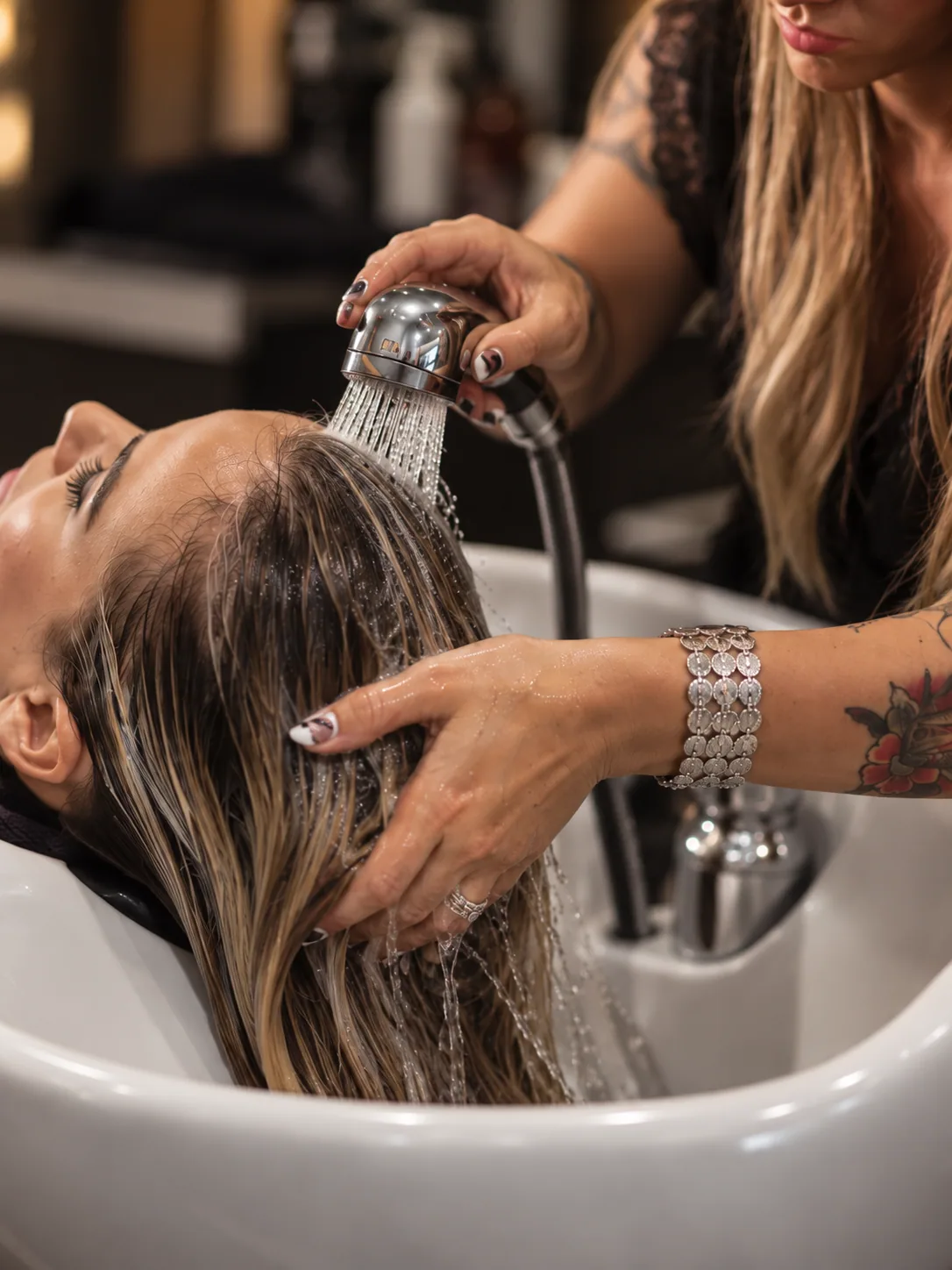 Stylist rinsing a client's hair at a salon basin