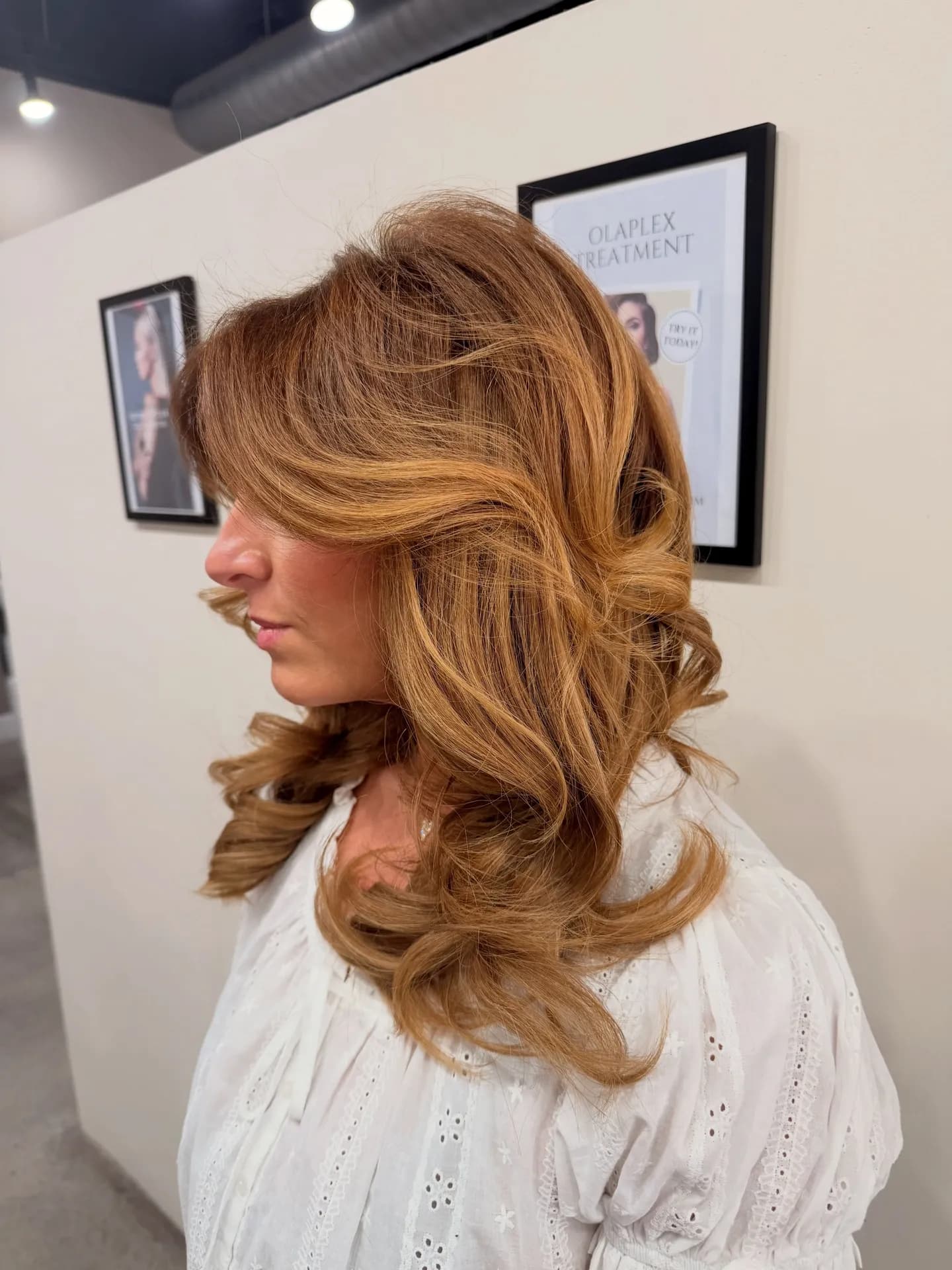 Honey-copper face-framing layers with full, bouncy volume, in profile
