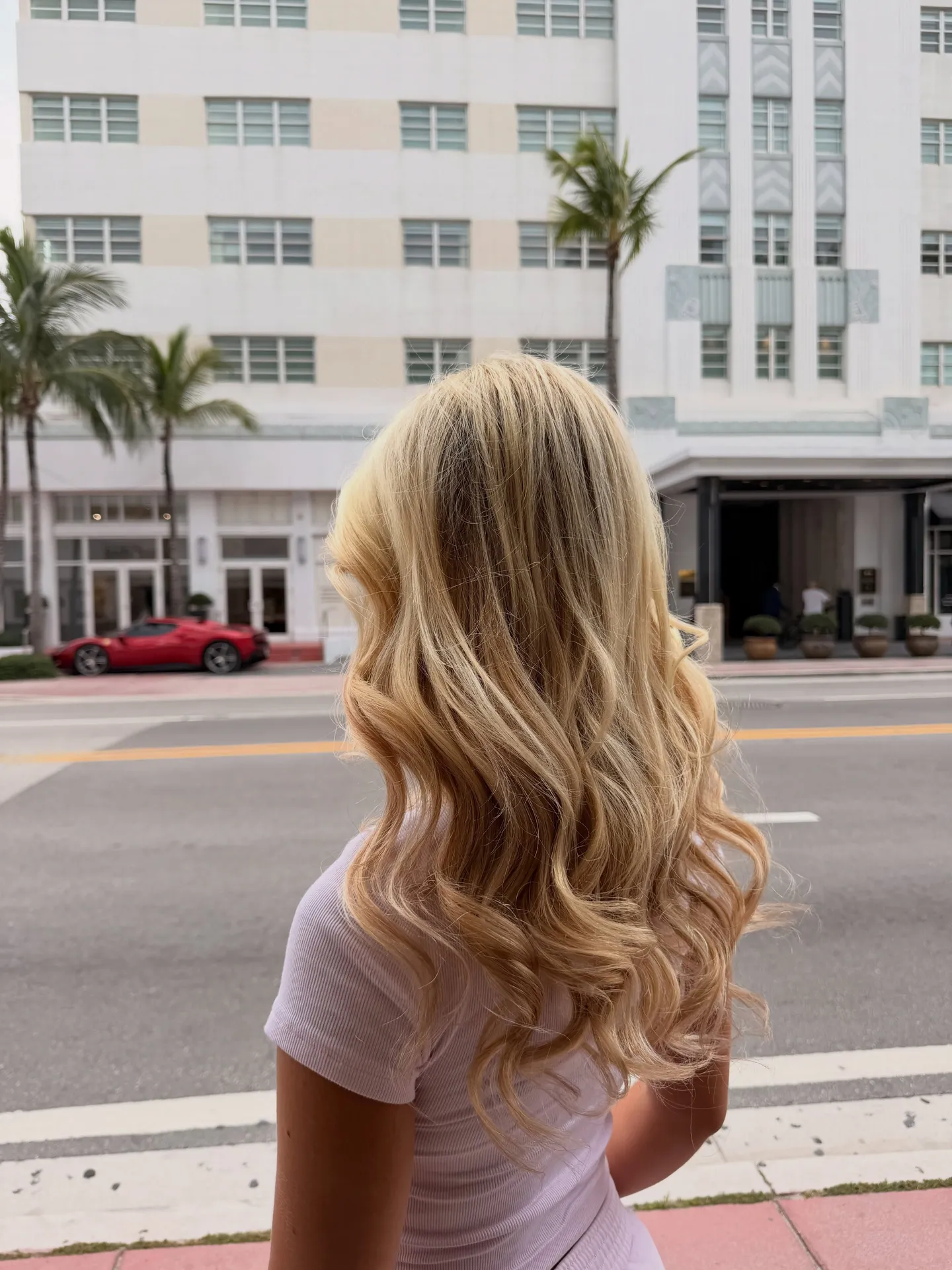Long blonde layers with soft waves, seen from behind on a Miami Beach street