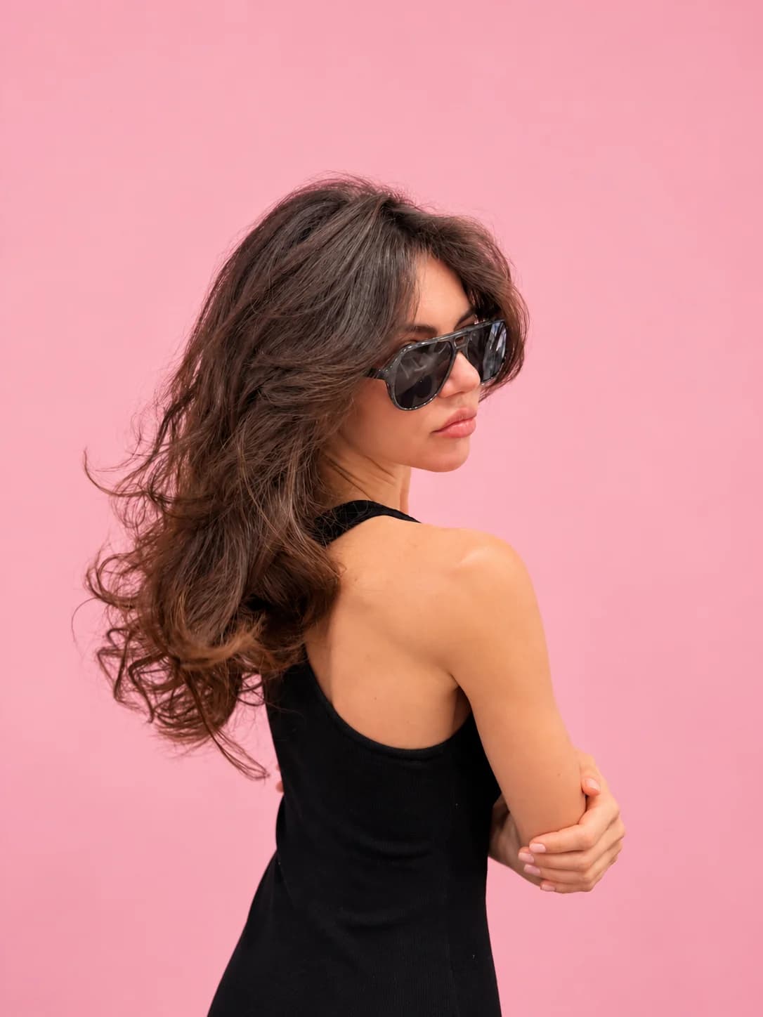 Long, voluminous brunette waves with soft layers, styled by Marlou, against a pink wall