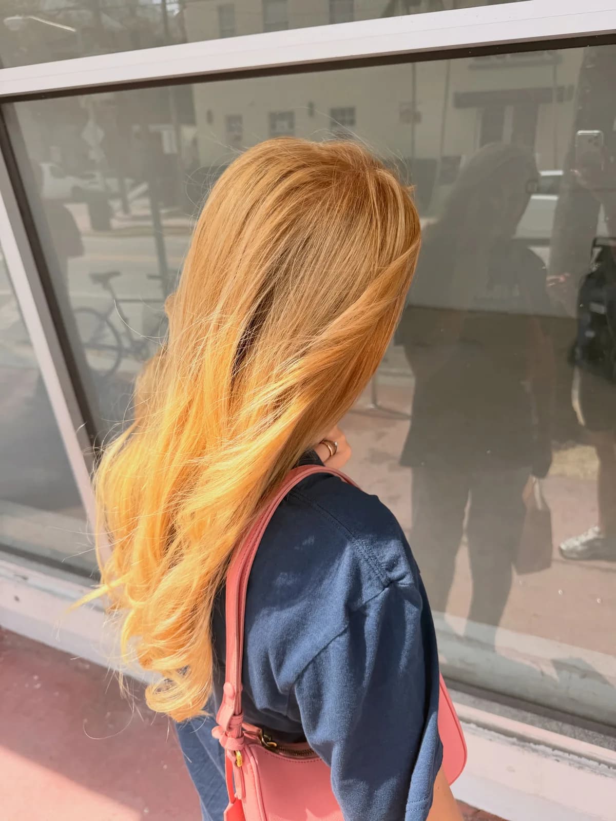 Golden blonde hair with soft waves seen from the side beside a storefront window
